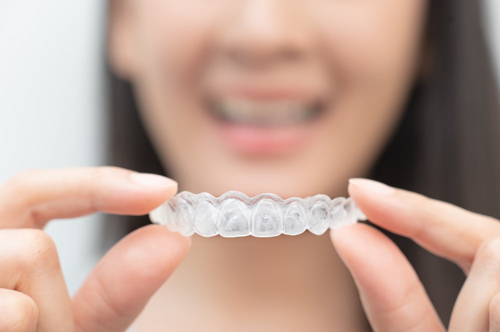 Visage flou d'une jeune femme avec, en avant-plan, sa gouttière Invisalign