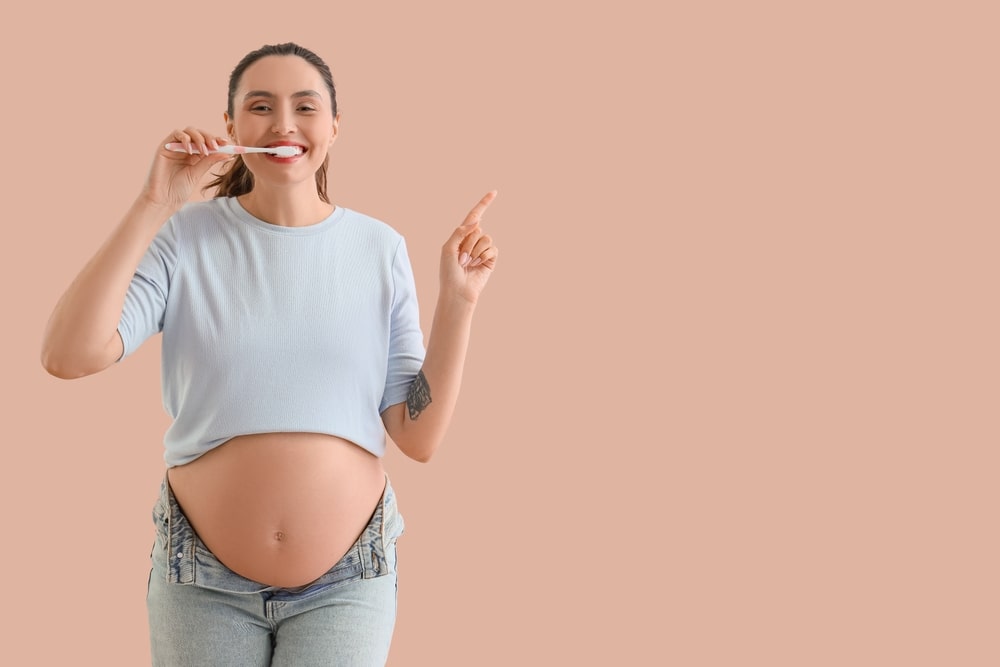 Une femme en cours de grossesse se brosse les dents