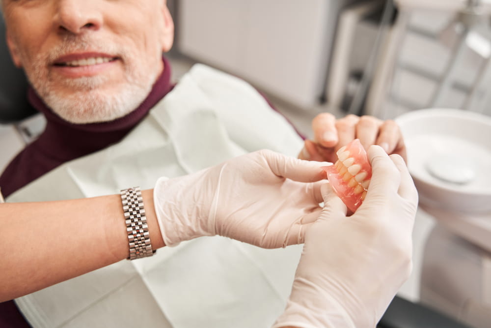 Un homme âgé reçoit sa nouvelle prothèse dentaire par son denturologiste